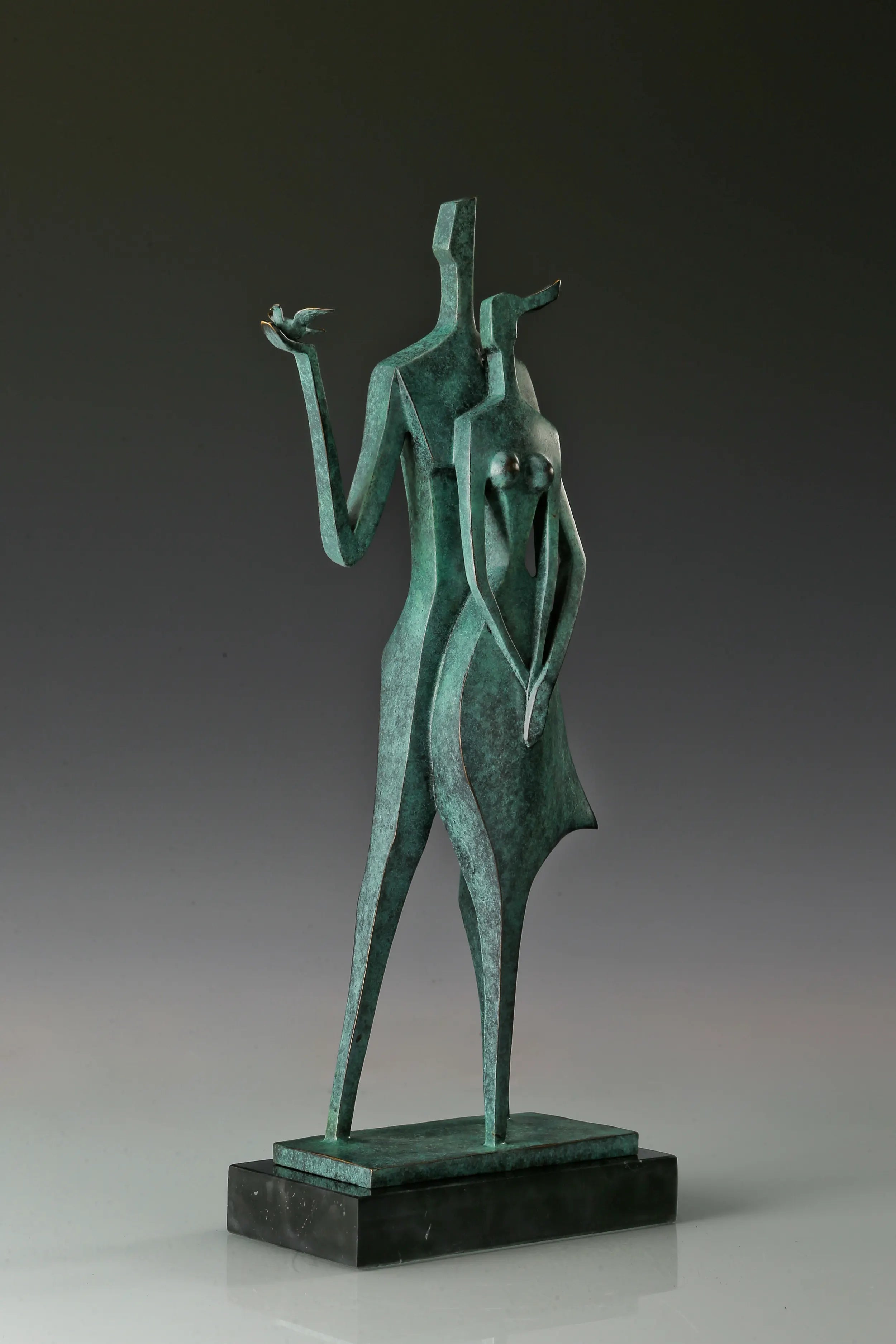Left angled view of abstract couple sculpture with a small bird held in an outstretched hand