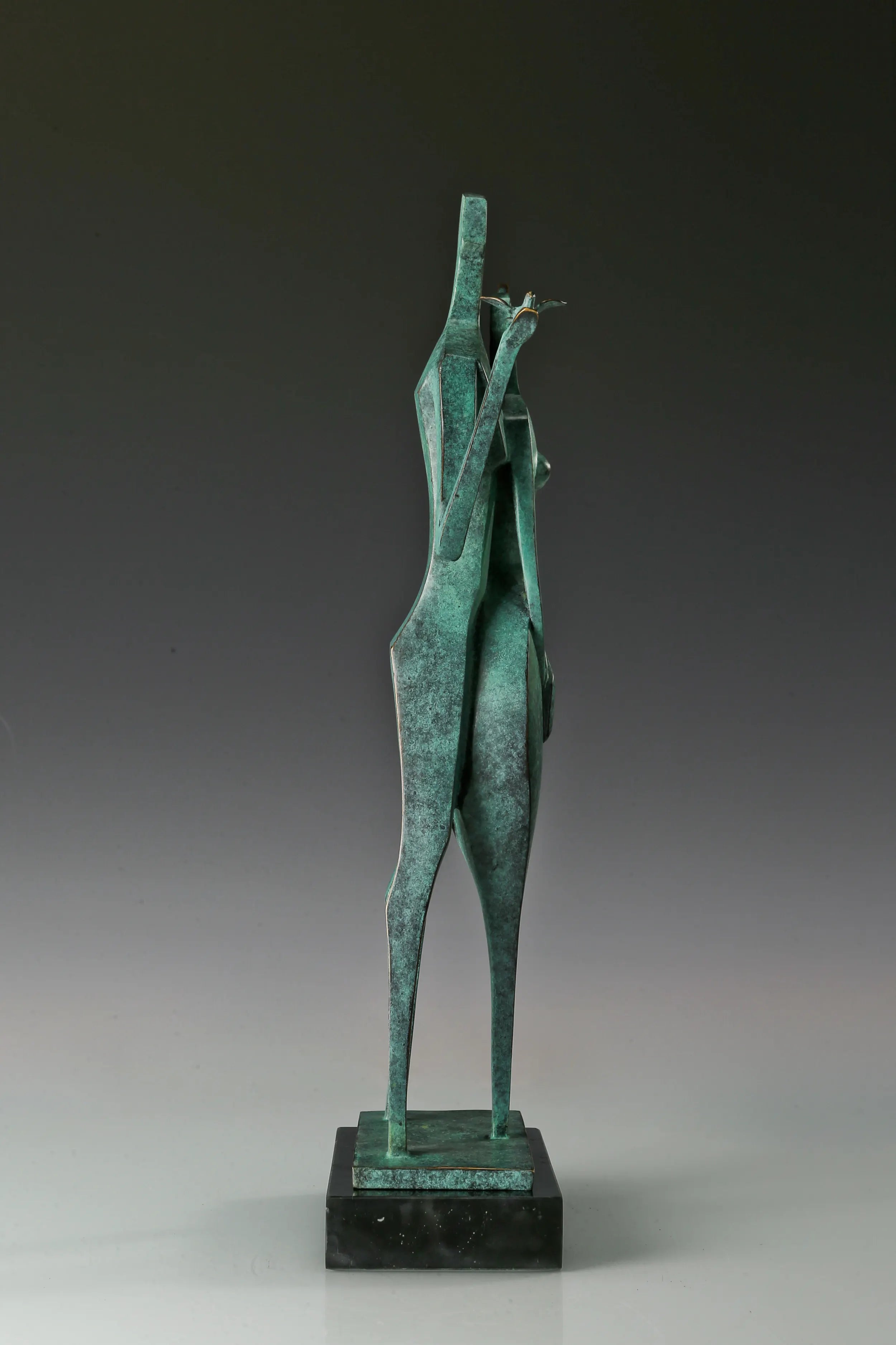 Left side view of two stylized bronze figures standing together on a black marble base