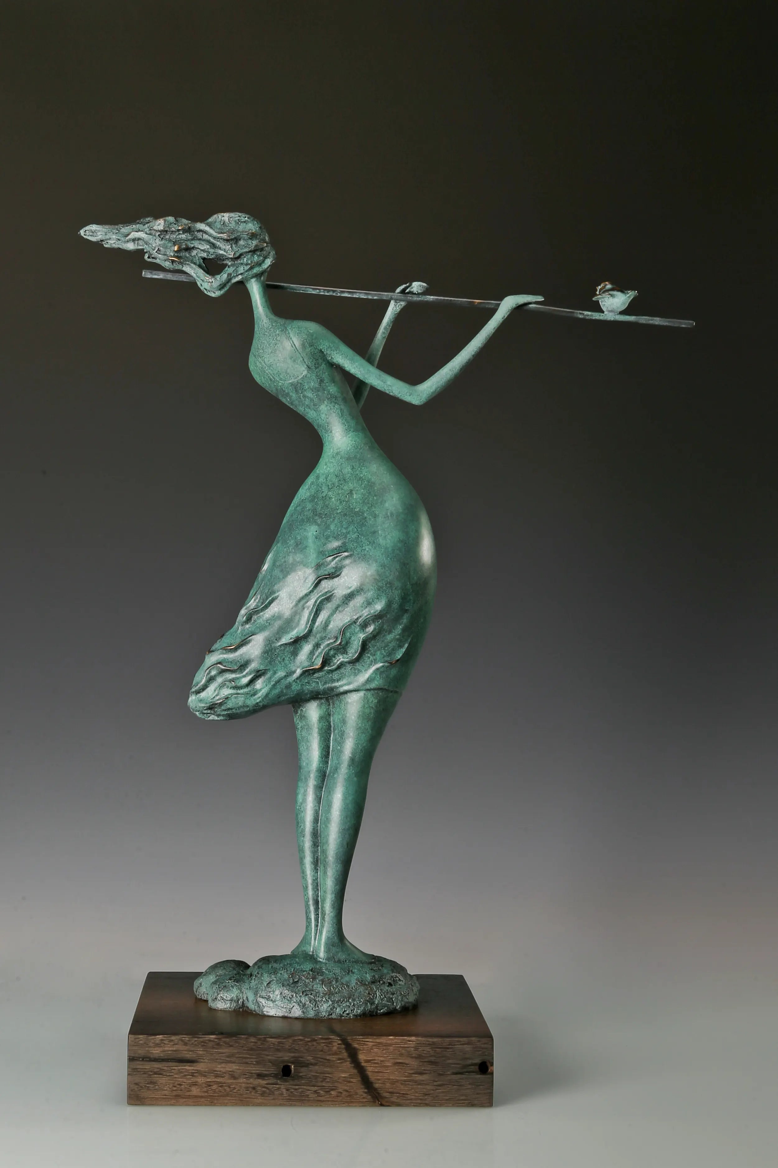 Back view of female flute player bronze statue showing her windswept hair and sculpted skirt