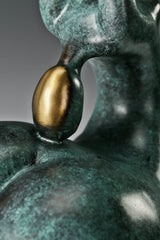 Close-up of gold-toned accent within the curved upper body of abstract gymnast sculpture