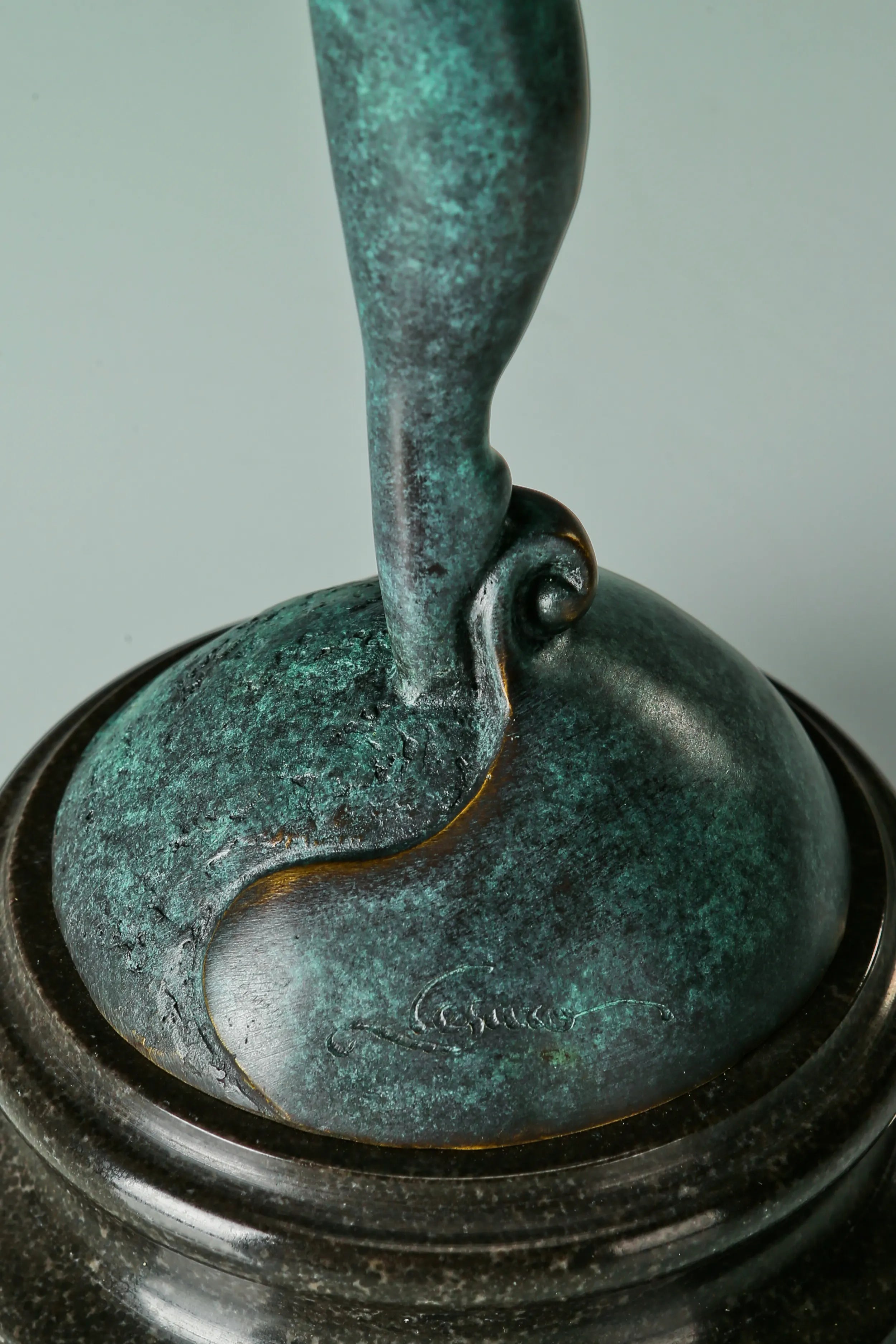 Detail of the gymnast sculpture's supporting leg and green patina above its black base