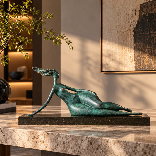 Abstract reclining woman bronze sculpture displayed on a marble table in a warm modern living room