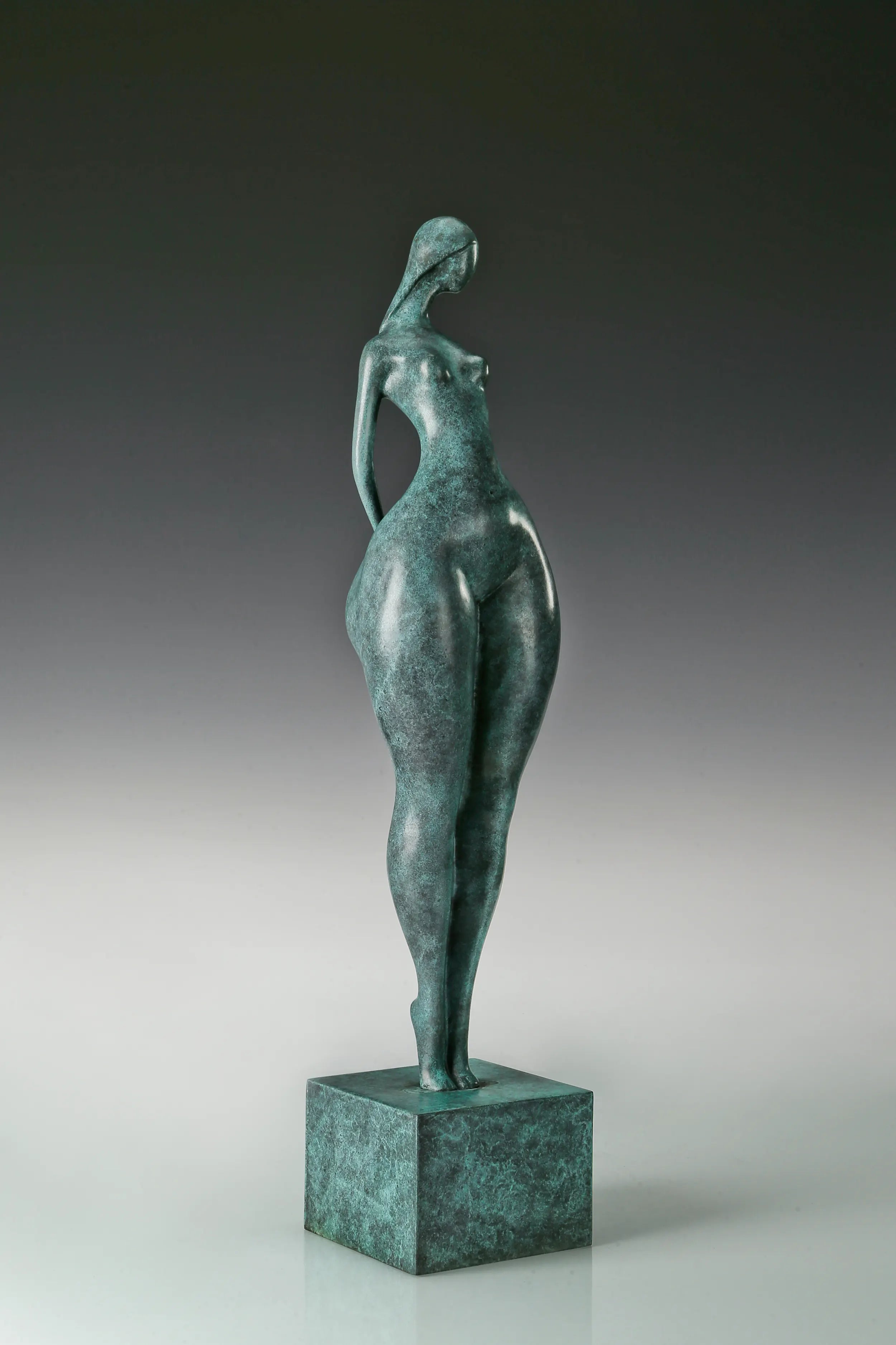Opposite side view of green patina bronze female figure standing on a square base