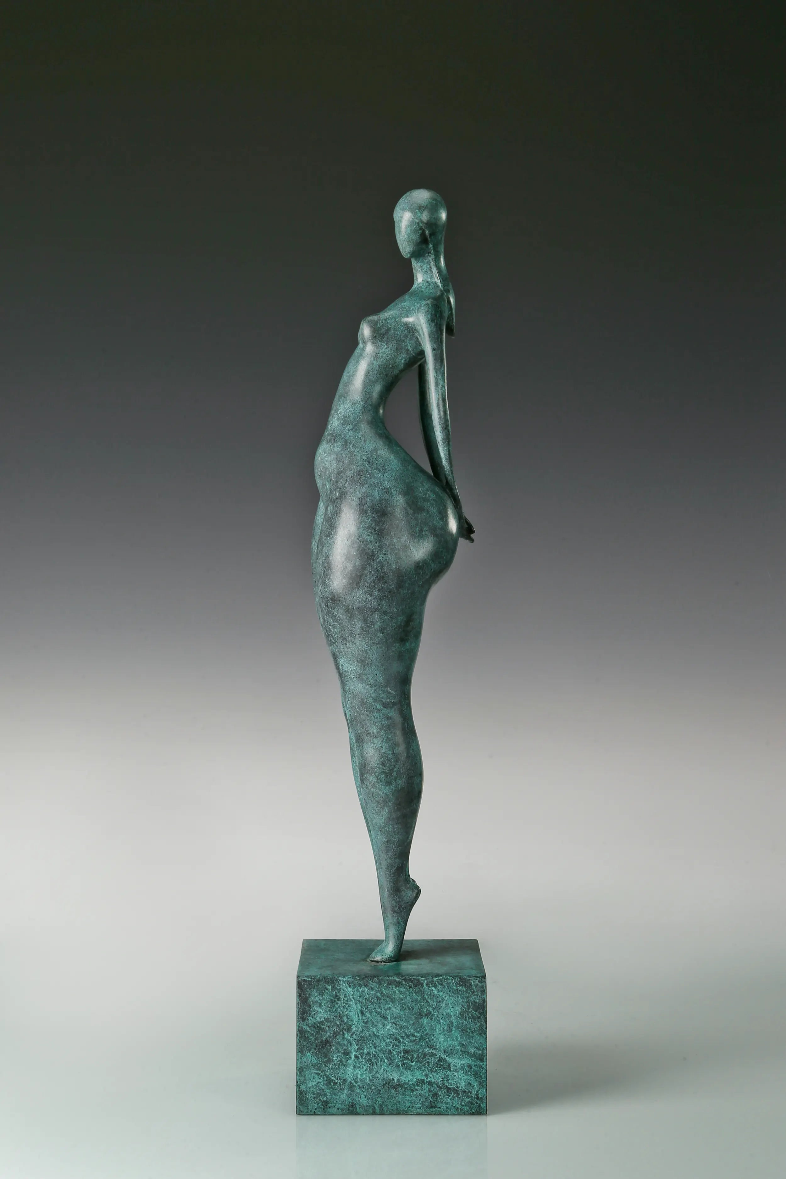 Side view of modern bronze standing woman sculpture showing its slender waist and curved silhouette