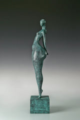 Side view of modern bronze standing woman sculpture showing its slender waist and curved silhouette