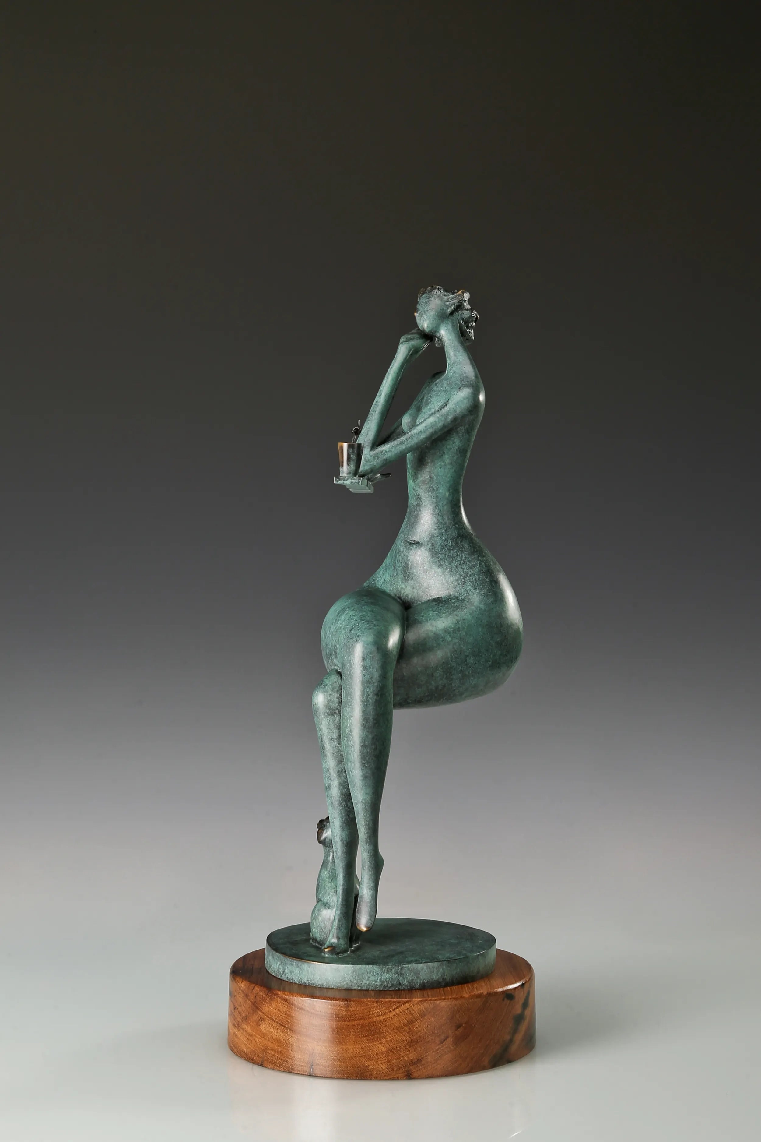 Side view of the seated woman bronze statue showing her relaxed posture and wooden base
