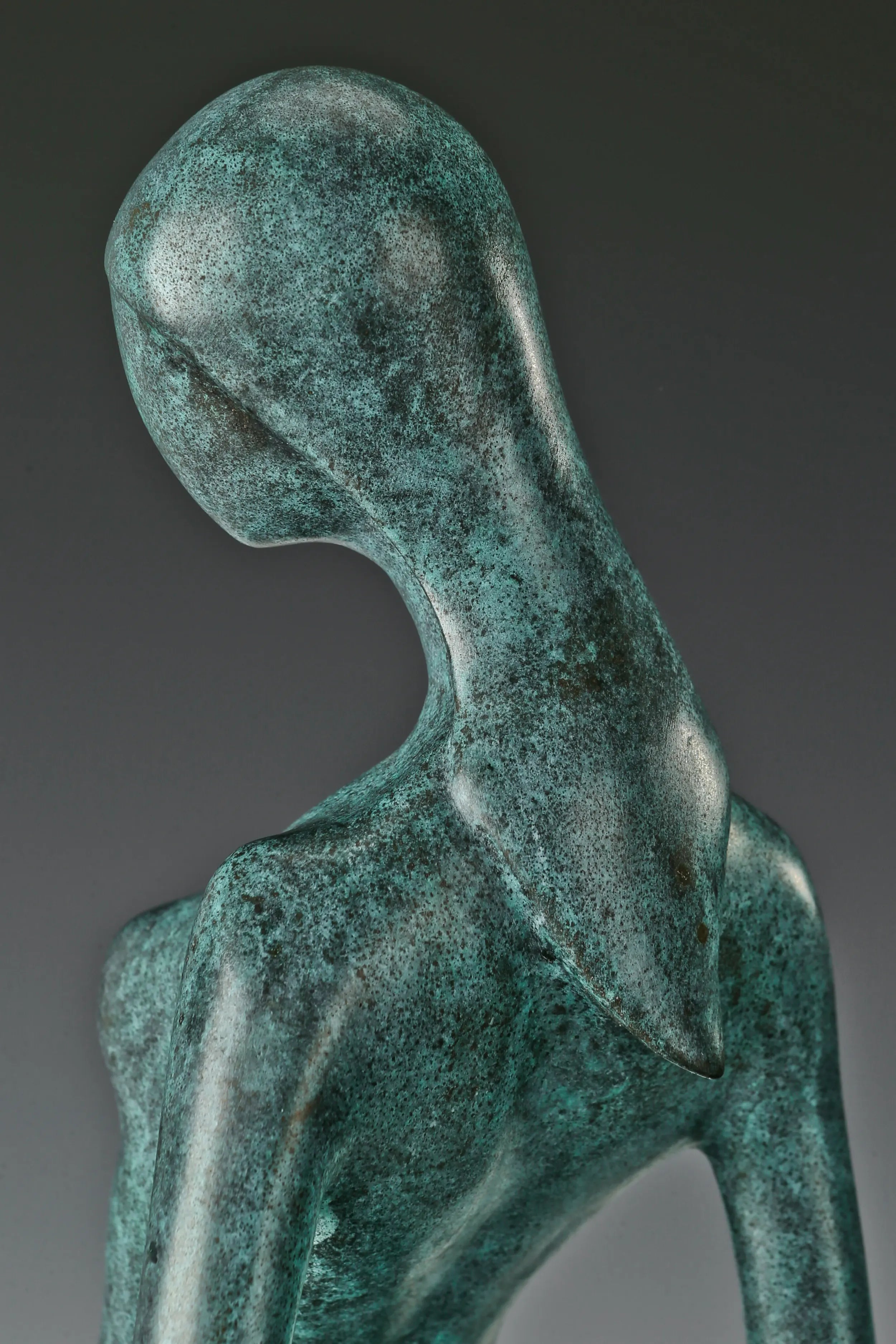 Side detail of the tilted head, neck, and shoulders of the bronze woman sculpture