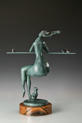Rear view of an abstract woman sculpture with flowing hair and a small cat at the base