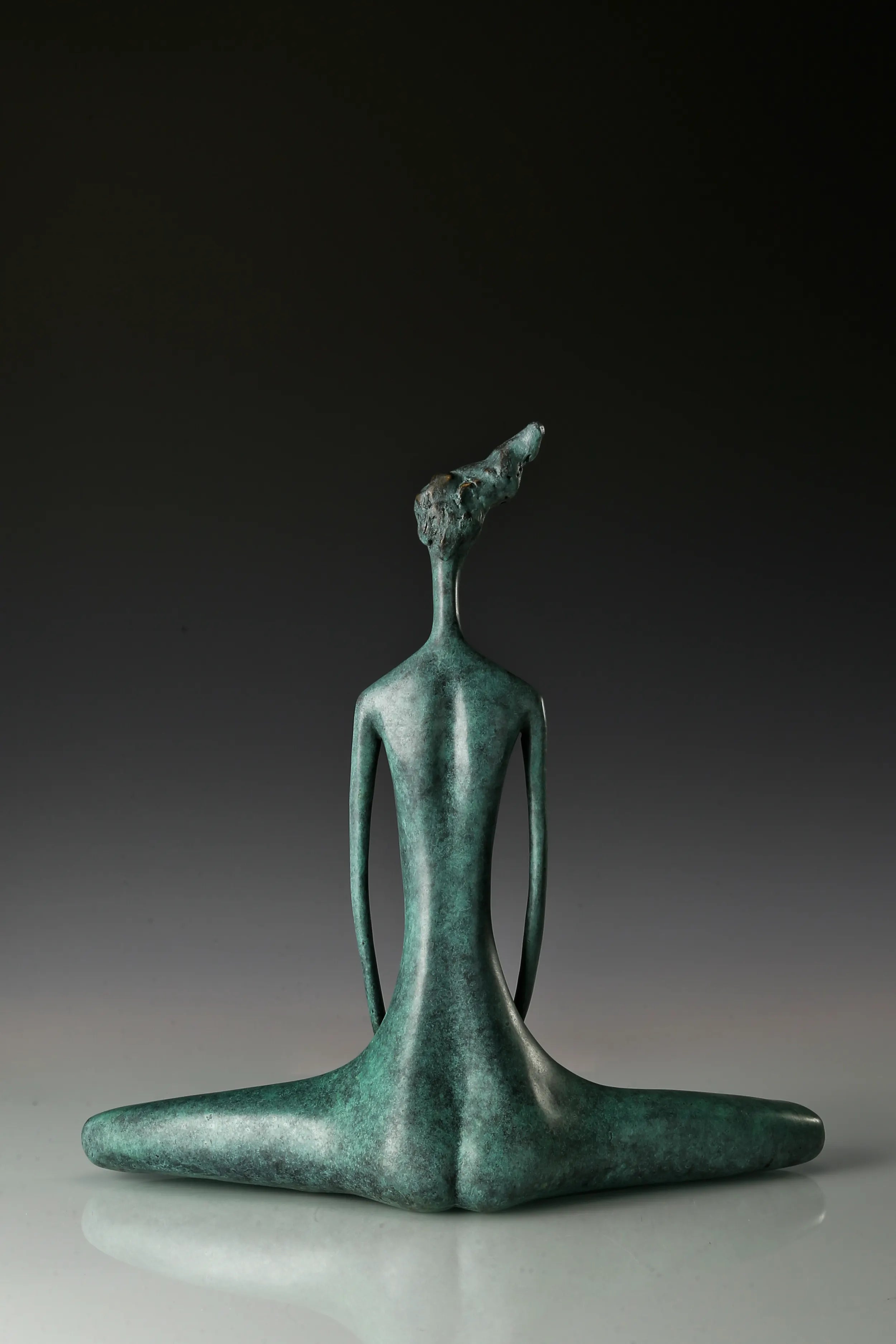 Back view of green patina bronze meditation figure with folded legs