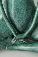 Close-up of the bronze woman's hands resting together in front of her folded legs