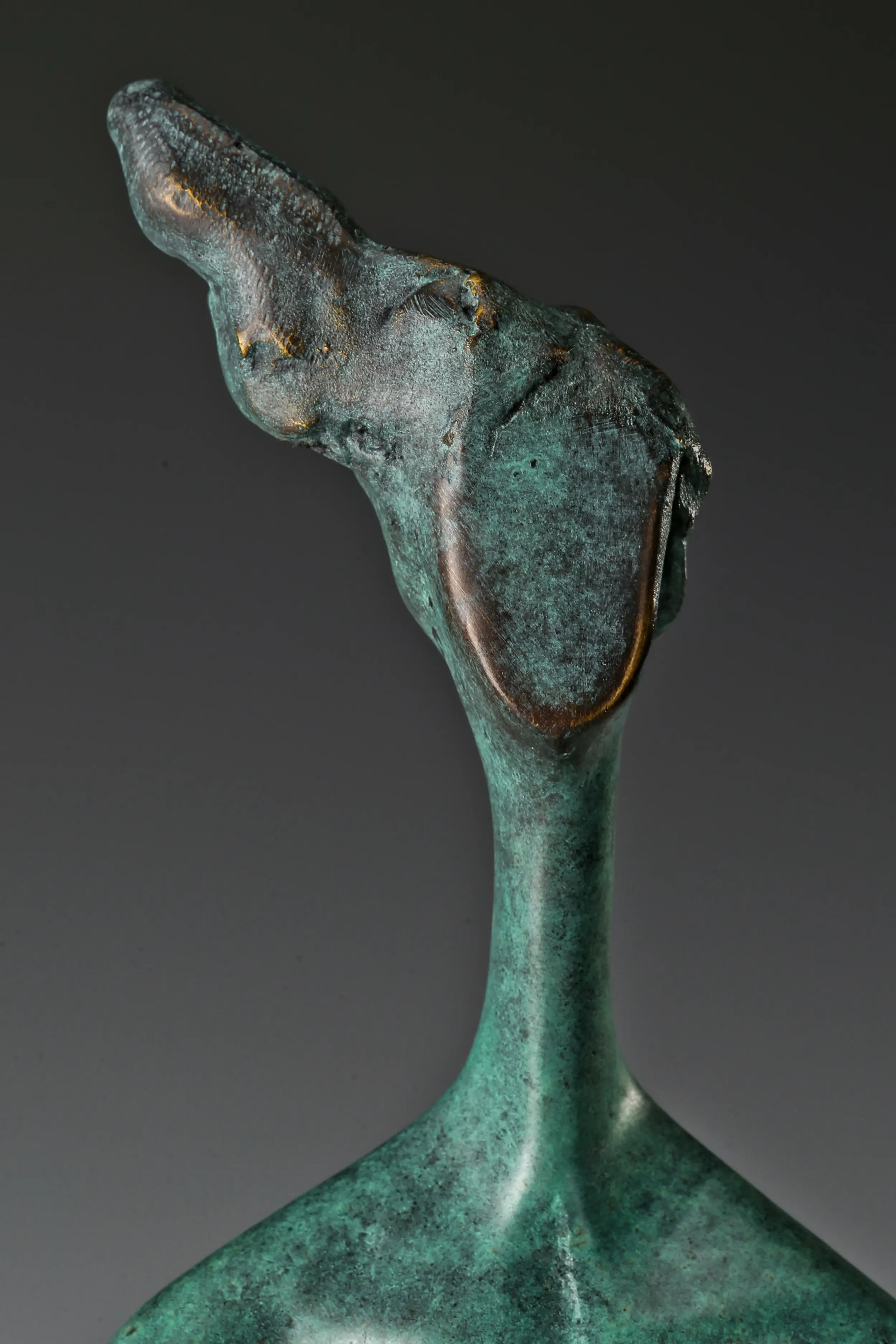 Close-up of abstract woman's upward-tilted head and textured bronze patina
