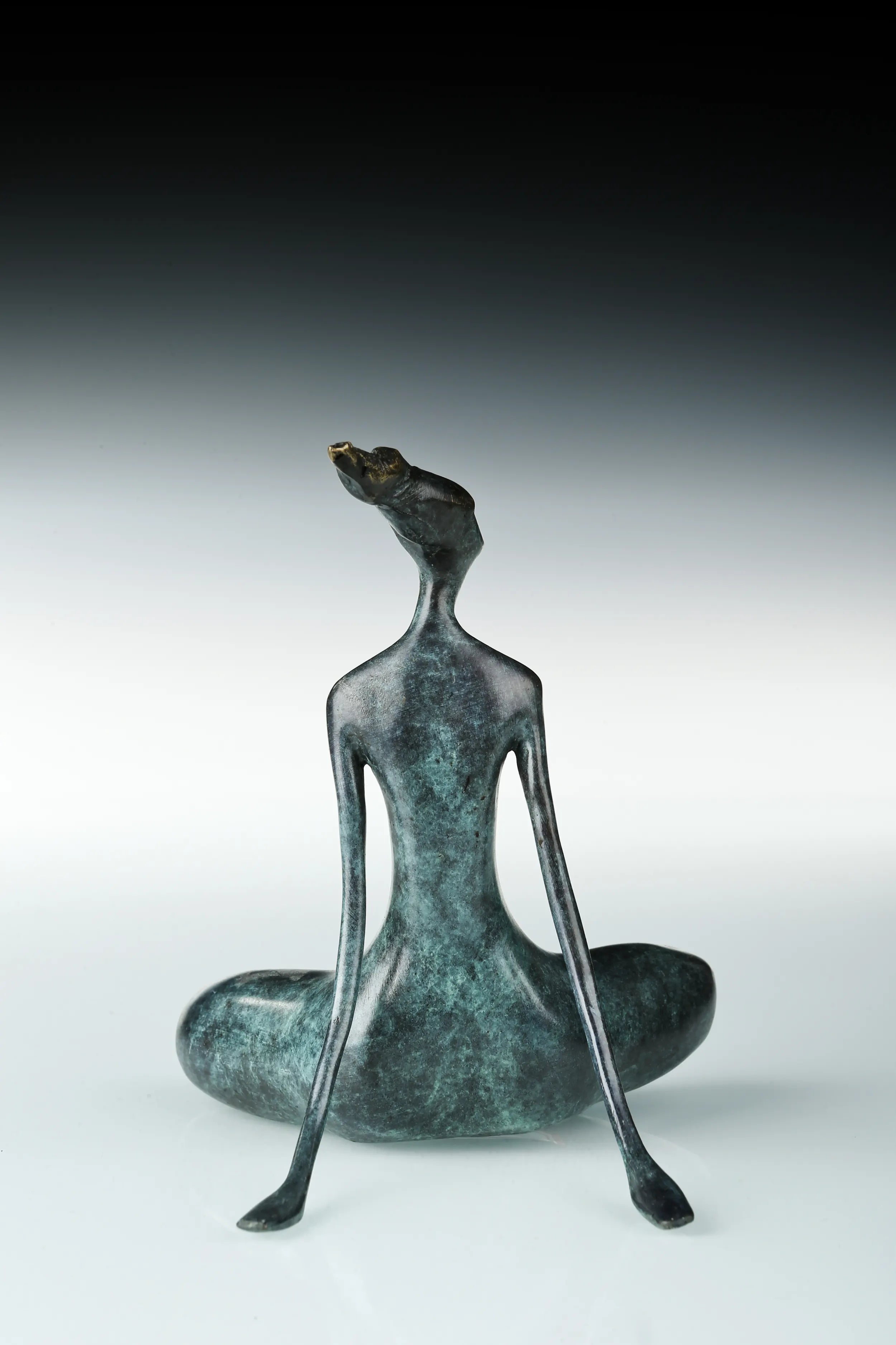 Rear view of abstract yoga woman statue with elongated arms and crossed legs