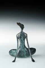 Rear view of abstract yoga woman statue with elongated arms and crossed legs