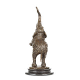 a highly expressive, abstract bronze sculpture of an elephant calf, crafted using the lost-wax casting method. The piece captures the young elephant in a playful, rearing pose—one front leg lifted, trunk curled high into the air, and head tilted upward—conveying a sense of unbridled joy, vitality, and whimsy.