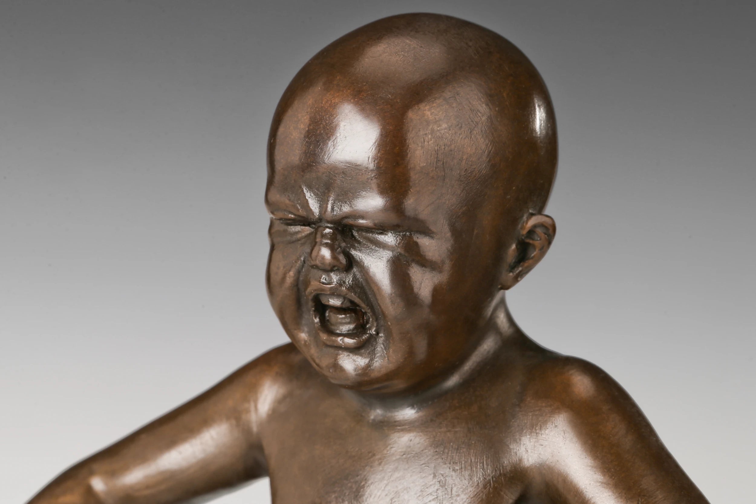 Close-up of the expressive angry face on a handcrafted bronze boy sculpture