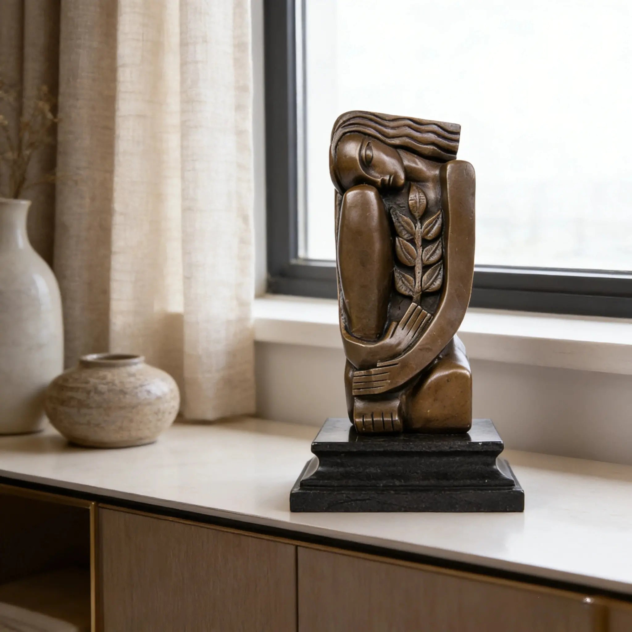 Art Deco seated female bronze sculpture with geometric design and olive branch detail