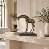 Bowing giraffe bronze sculpture displayed in an elegant modern interior