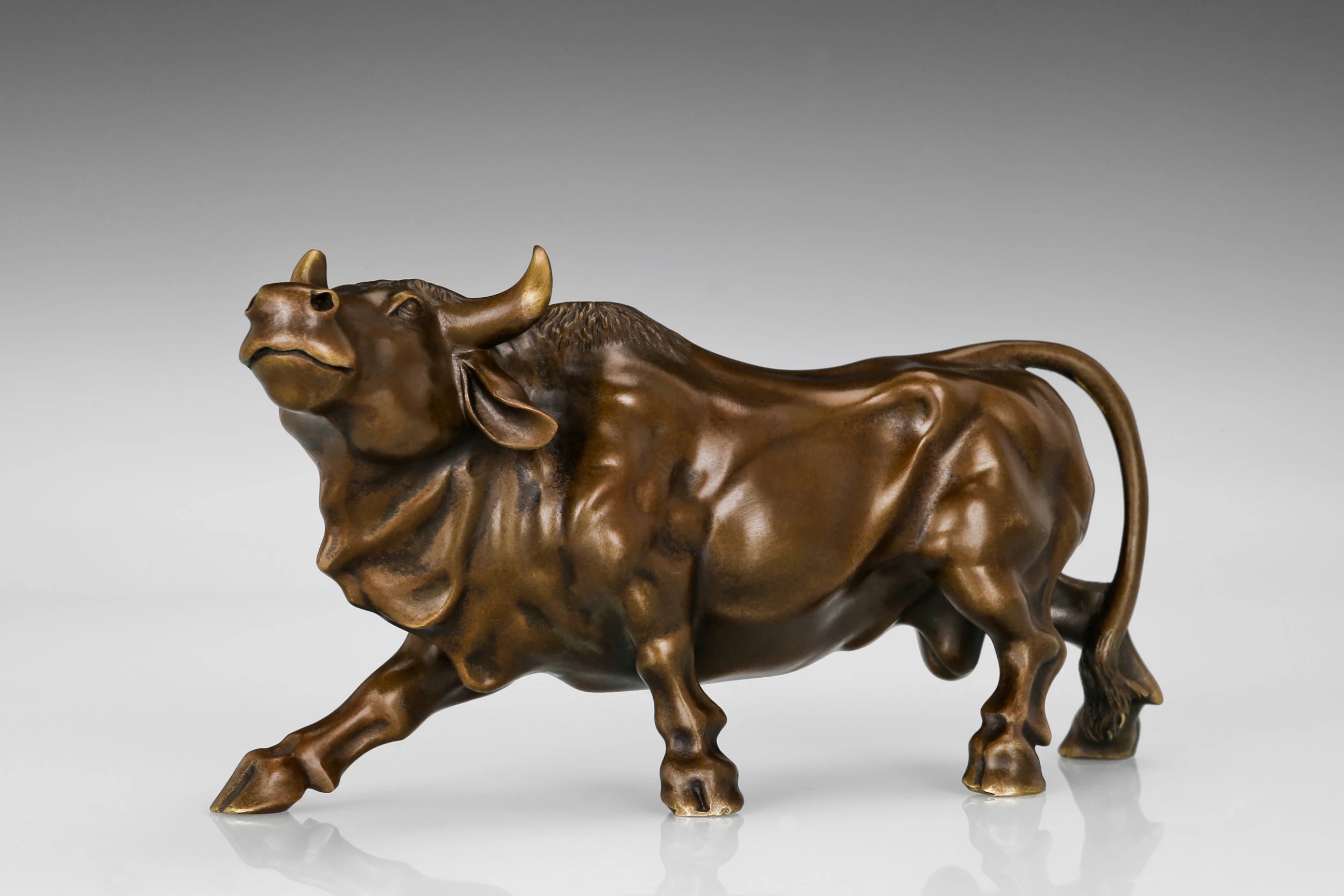 Side profile of a handcrafted bronze bull sculpture with realistic muscular details.