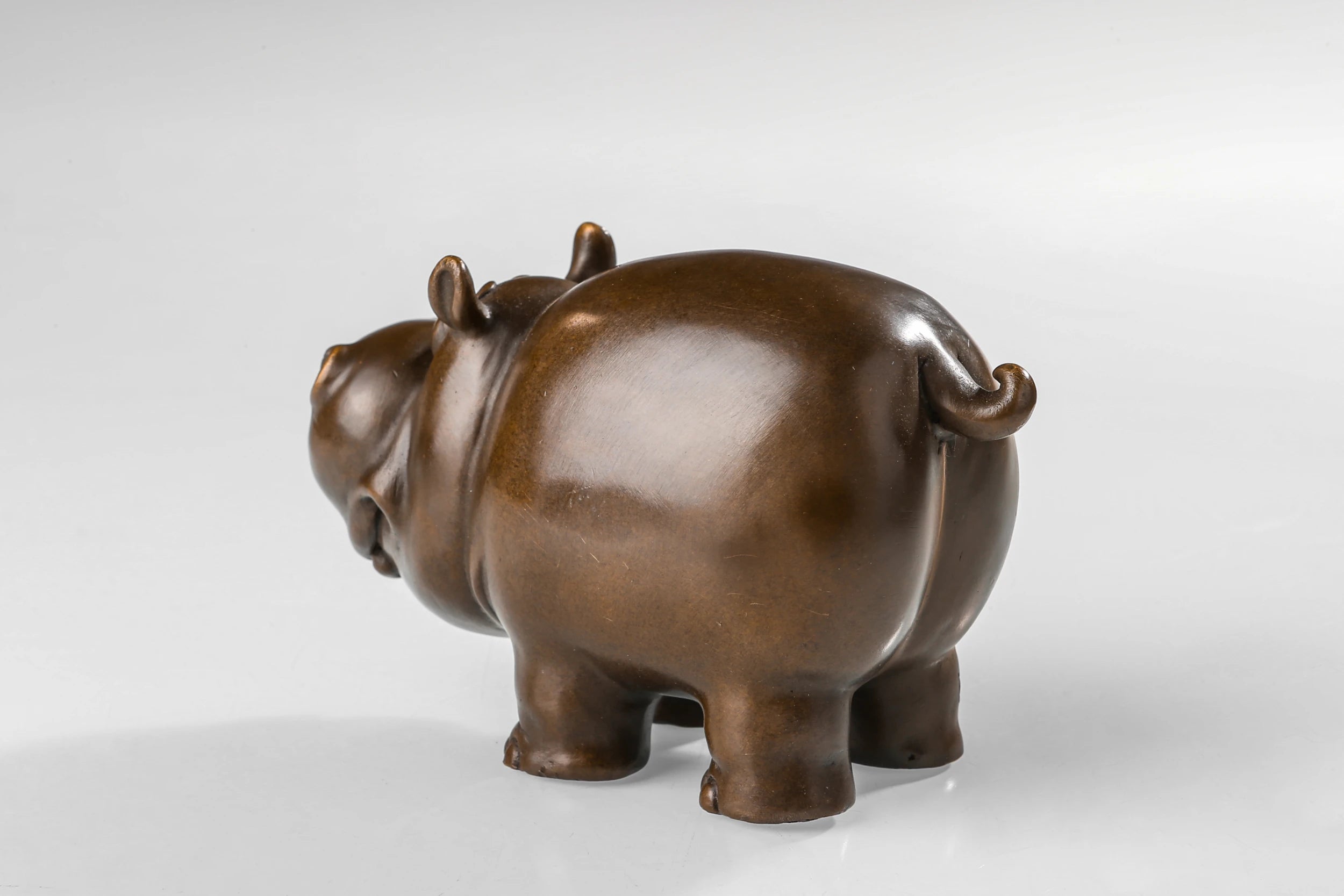 Side view of a solid bronze cartoon cow statue with a warm bronze patina.