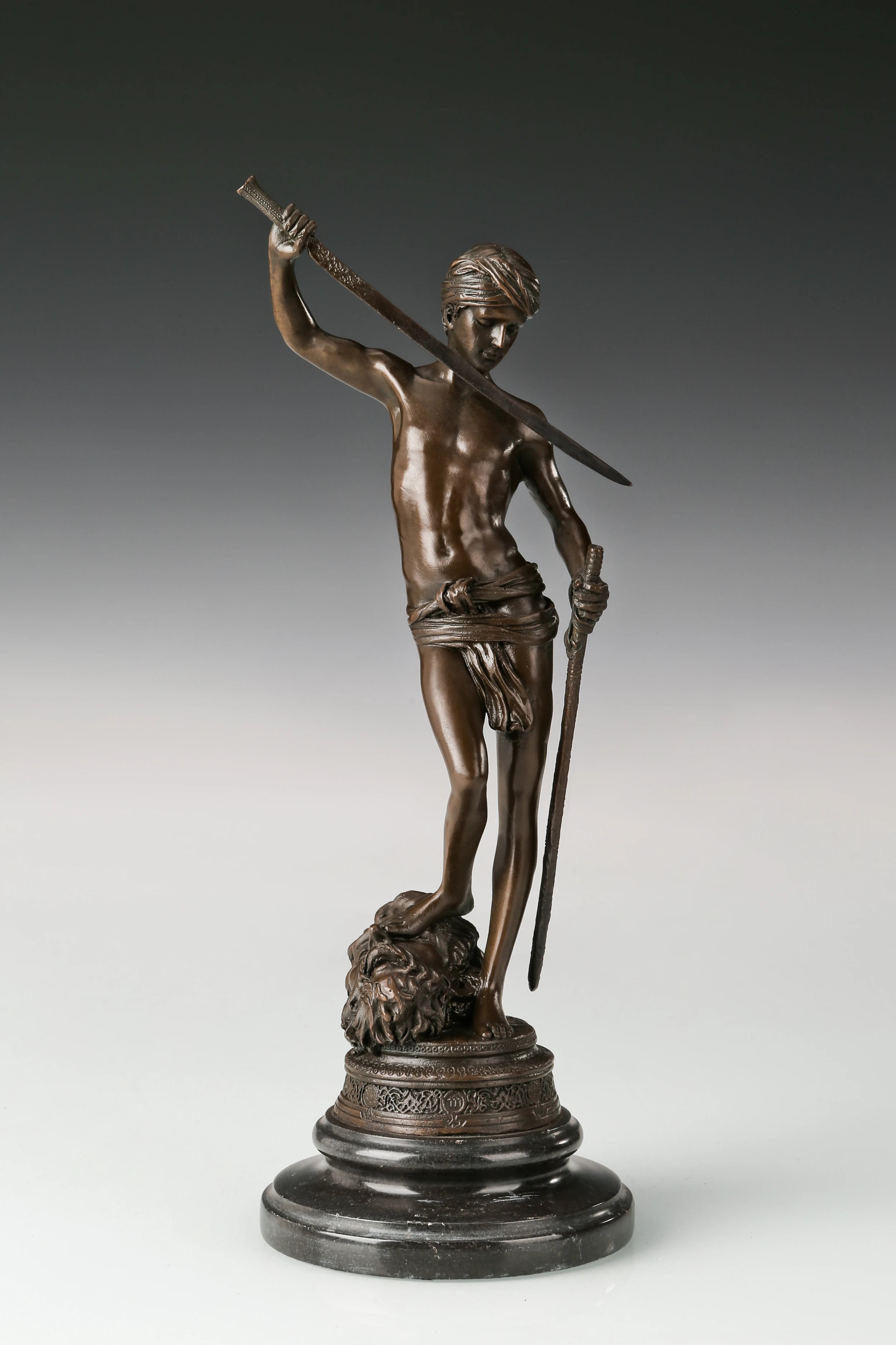 Front left angle of bronze David standing over Goliath sculpture