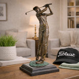 Handcrafted bronze female golfer swing sculpture displayed in a modern office interior.
