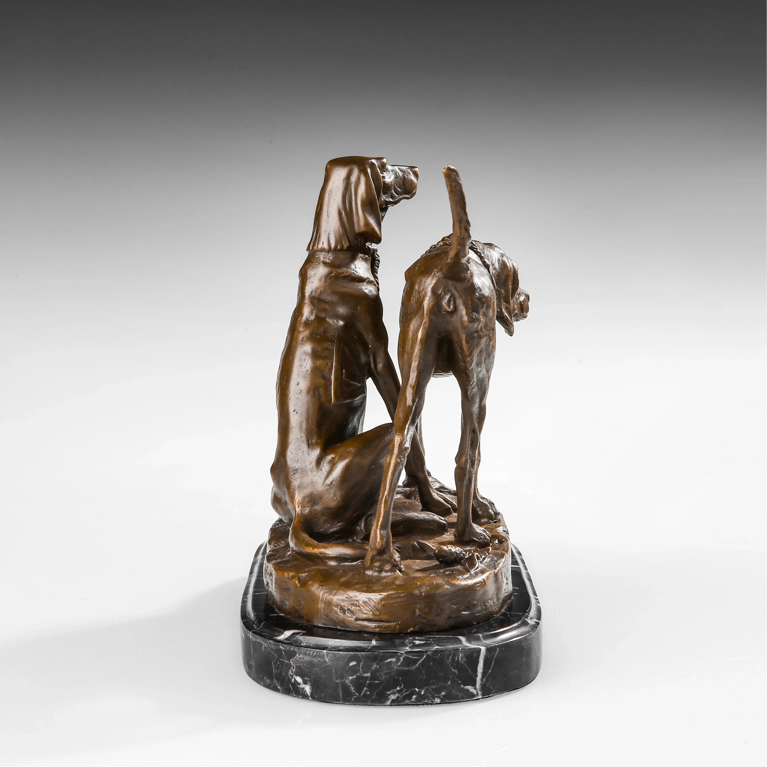 Rear view of bronze hunting dog pair sculpture showing body contours tails and layered composition