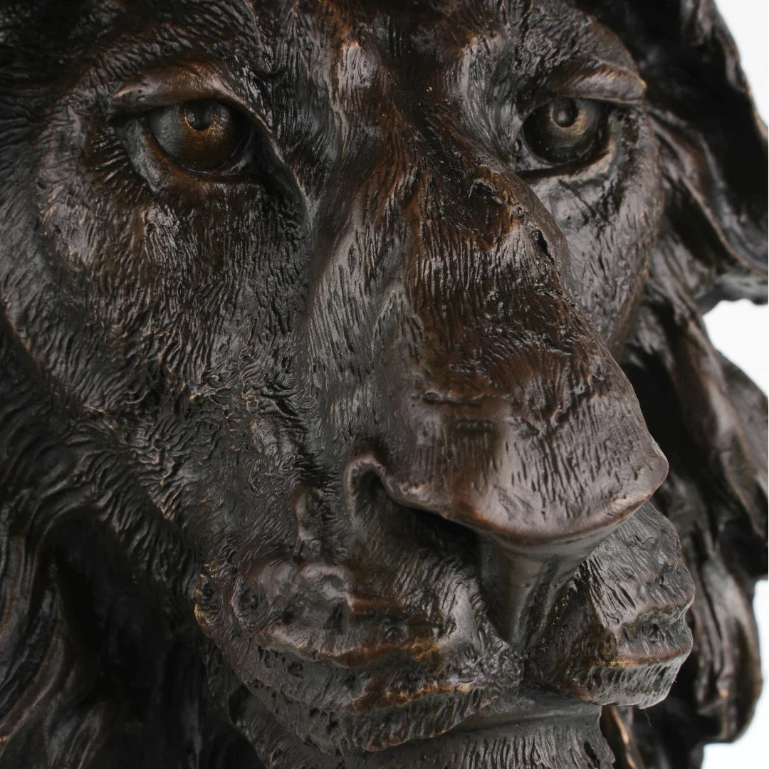 Close-up of bronze lion sculpture showing expressive face eyes and deeply textured mane