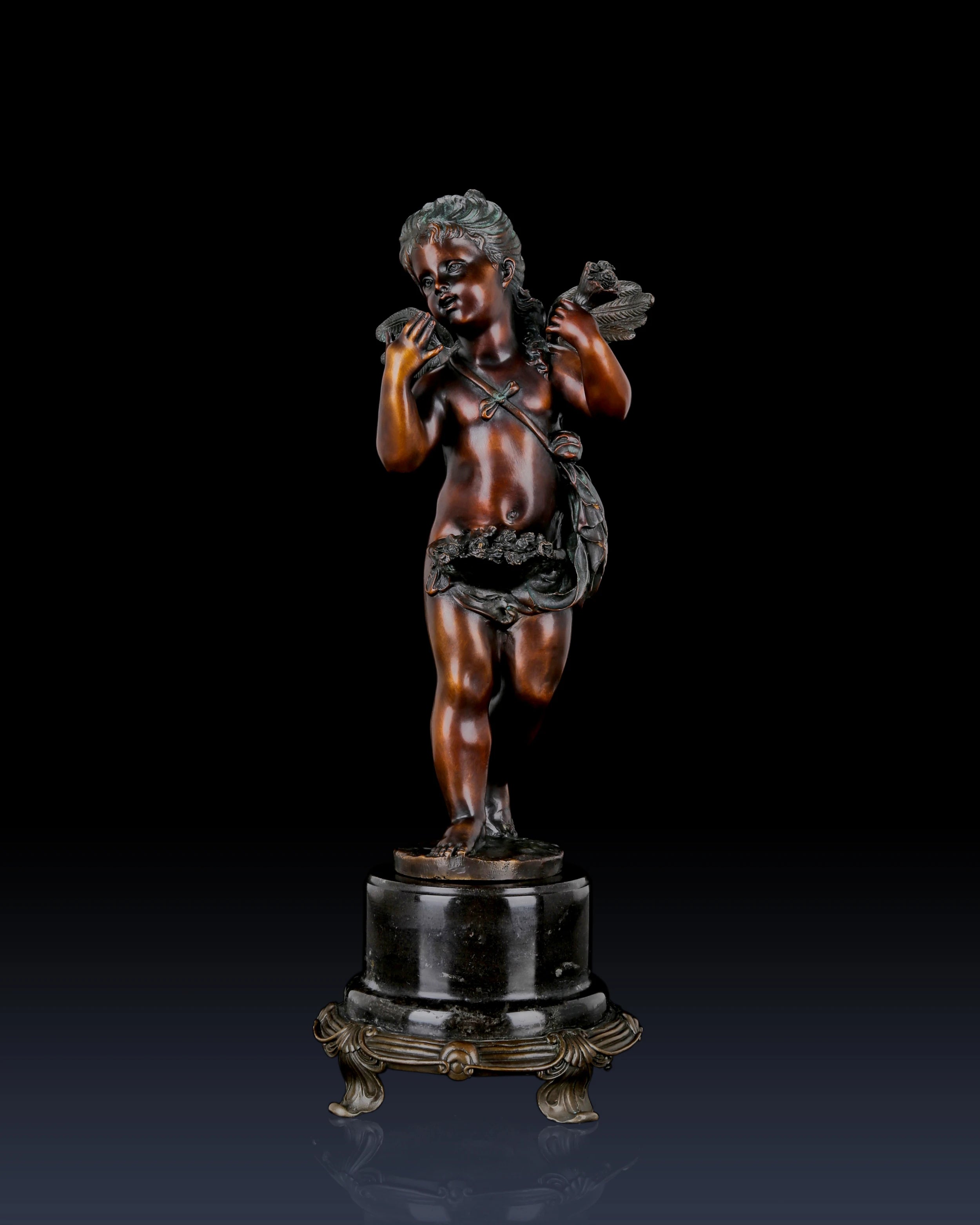 Three-quarter view of a bronze Putto cherub sculpture with classical decorative details