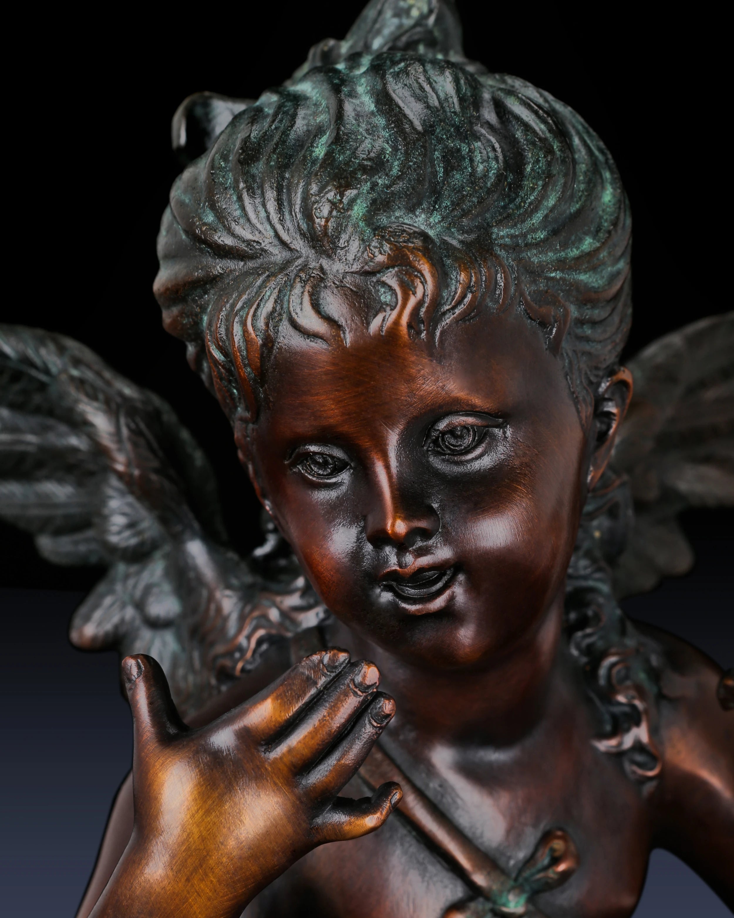 Close-up of the expressive face and curly hair of a handcrafted bronze Putto figure