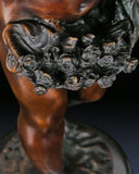 Ornate natural marble base supporting a handcrafted classical bronze Putto statue