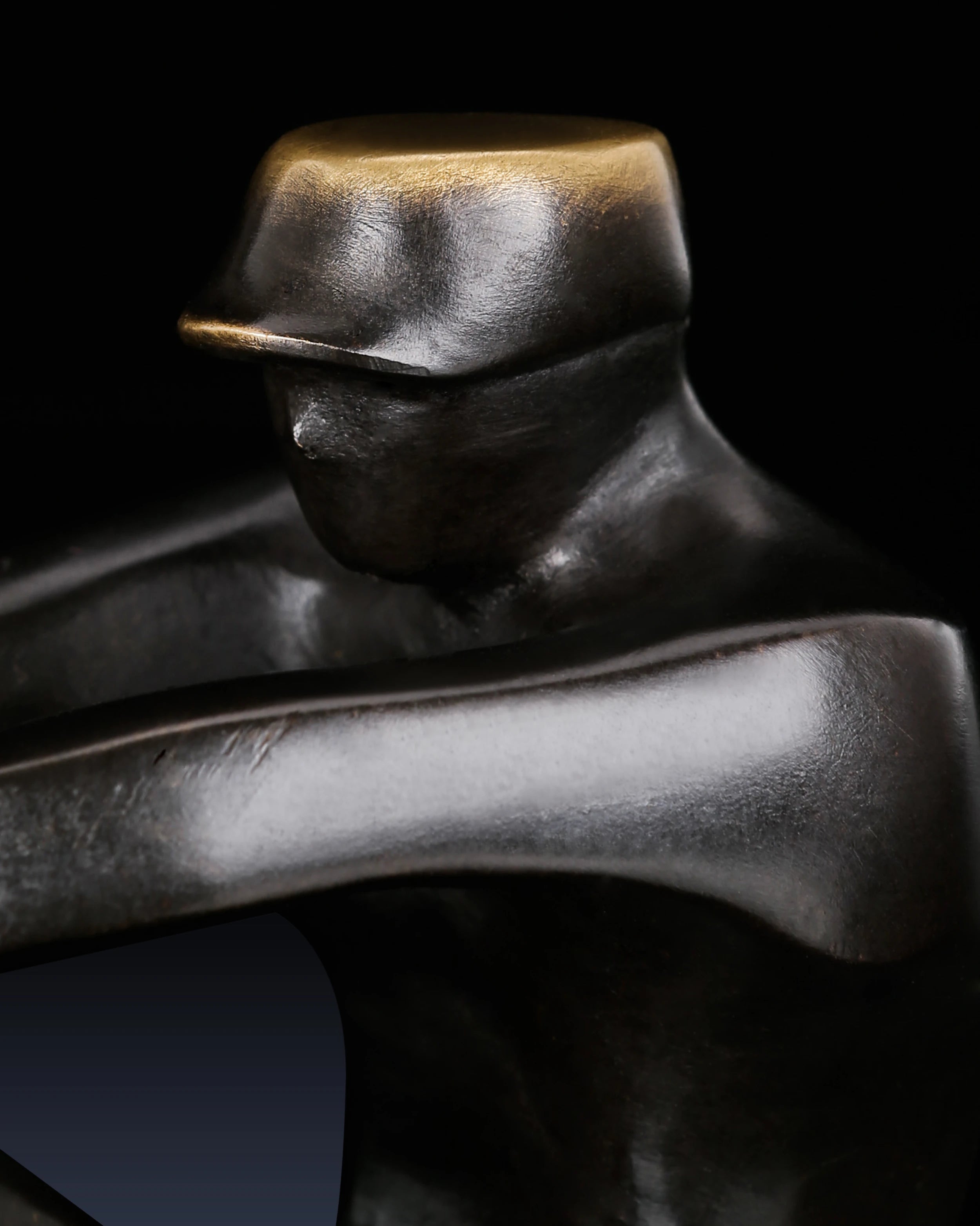 Close-up of seated sailor figure on handcrafted abstract bronze sailing sculpture