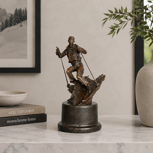 Bronze skier statue displayed as winter sports decor in a modern ski lodge interior.
