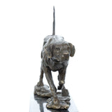 Close-up of bronze pointing hunting dog showing lowered head, detailed collar, and raised tail