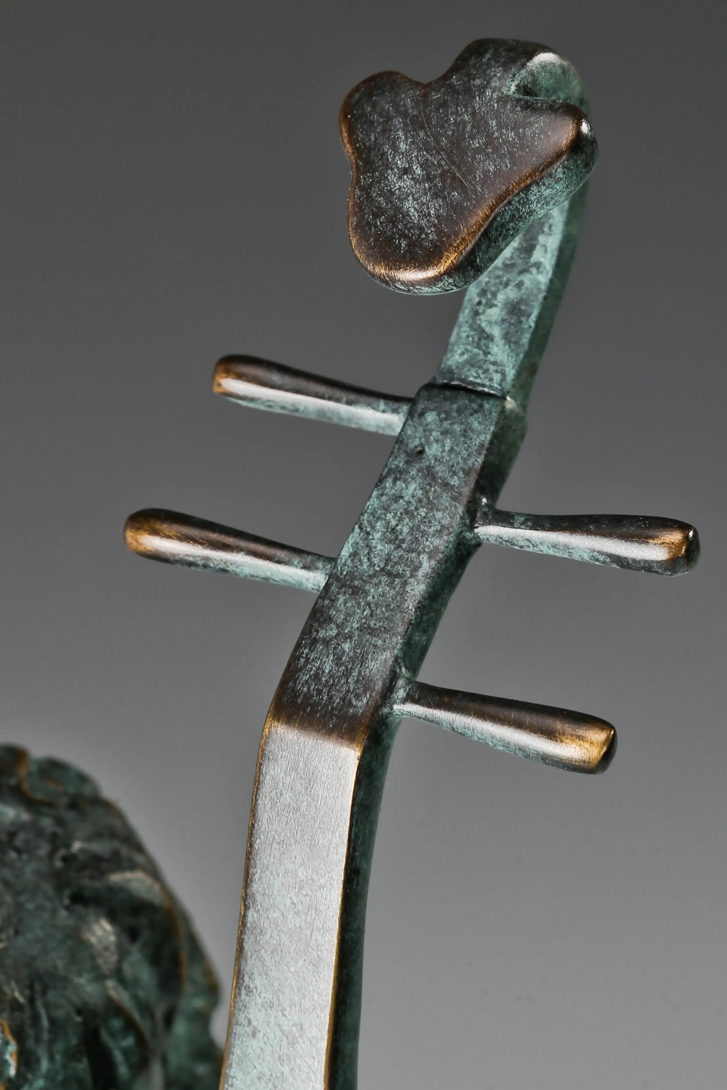Close-up of the Chinese pipa's long neck, tuning pegs, and bronze surface details