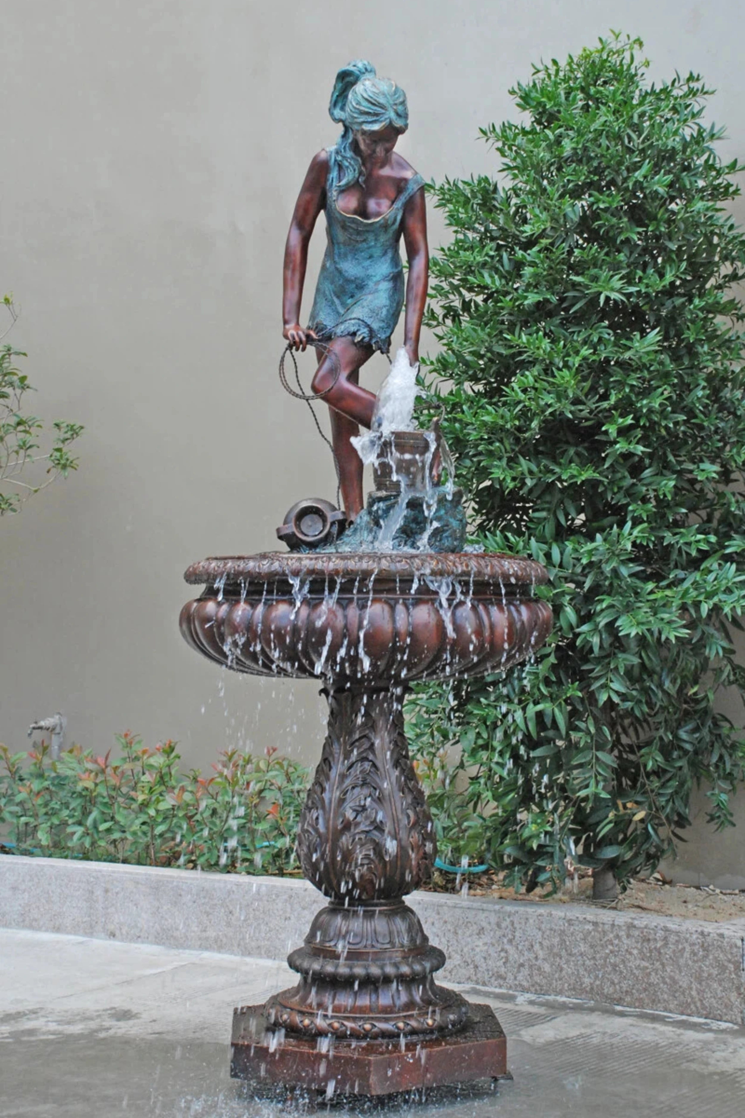 Classical bronze lady water fountain statue pouring water from a jug into a decorative garden basin