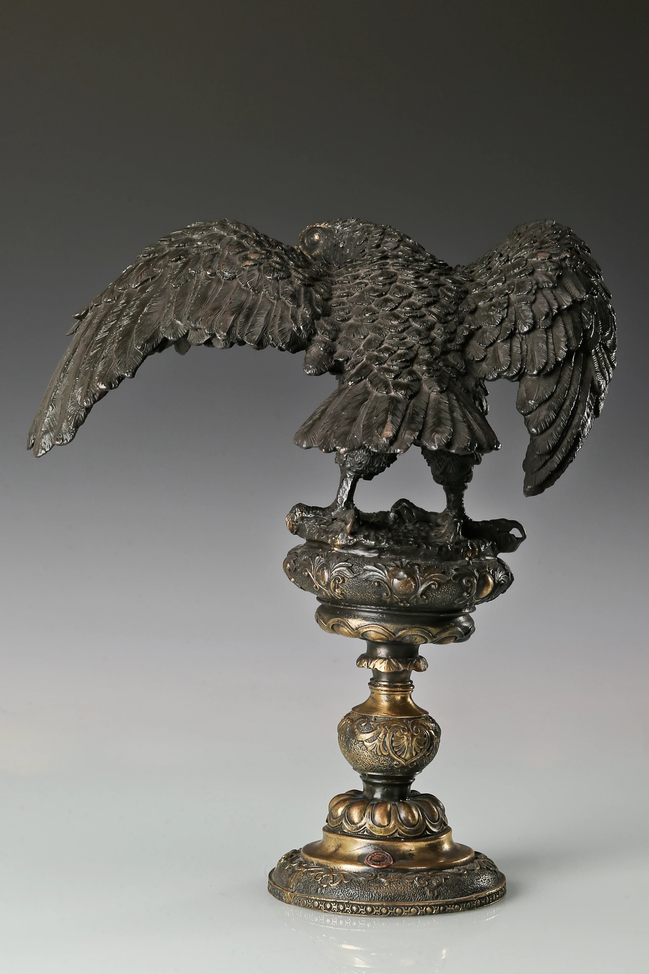 Elegant bronze eagle sculpture with ornate pedestal and detailed feathers. A refined statement piece symbolizing strength, control, and authority.