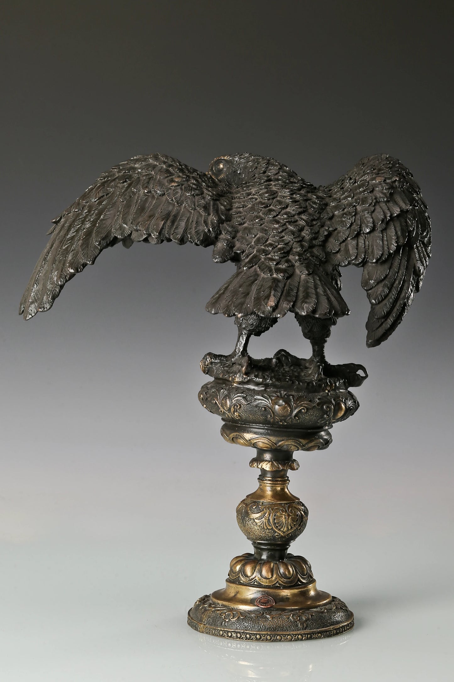 Elegant bronze eagle sculpture with ornate pedestal and detailed feathers. A refined statement piece symbolizing strength, control, and authority.