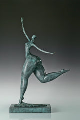 Left side view of green patina contemporary female dancer statue with a raised leg
