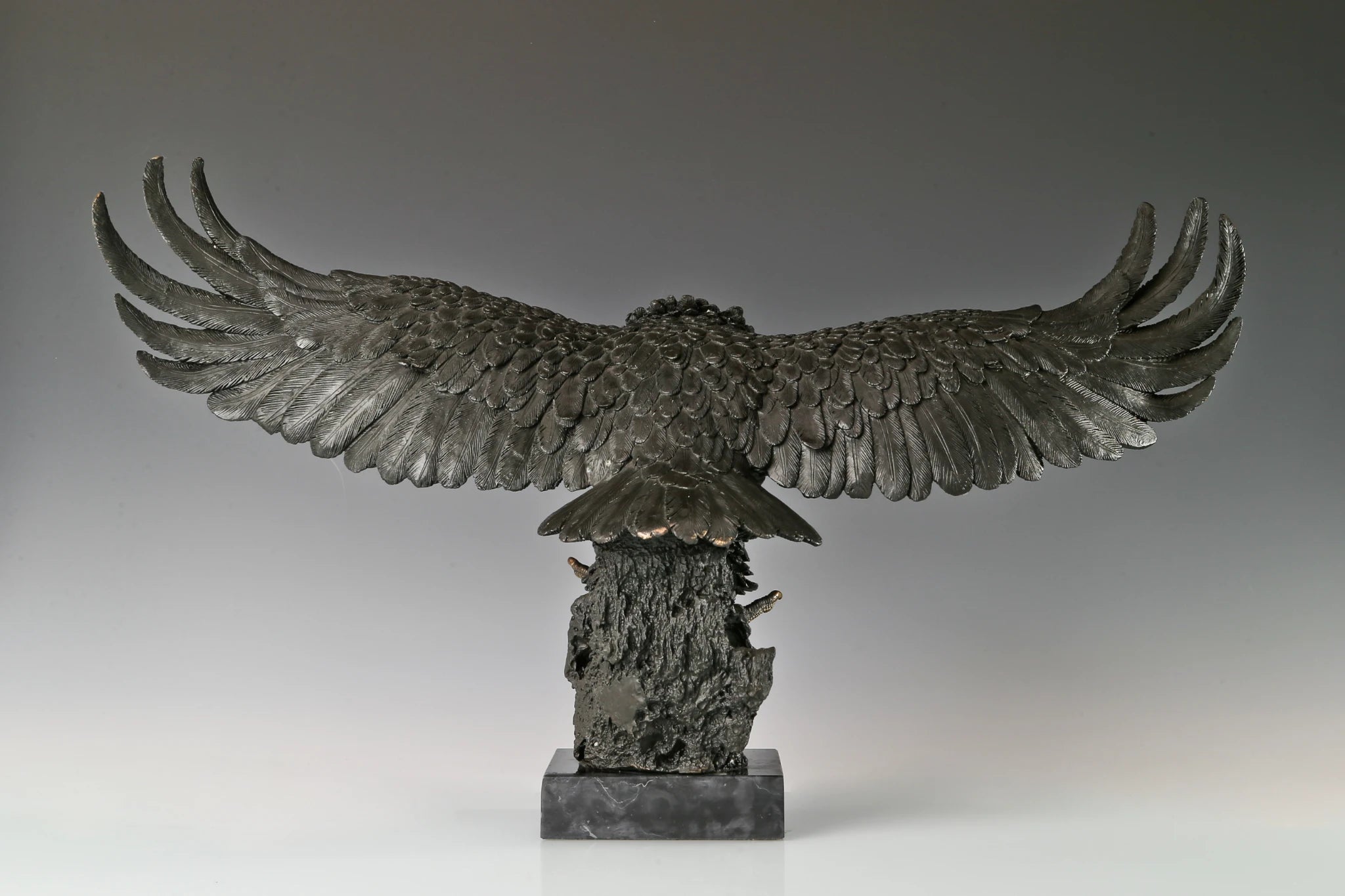 This majestic bronze sculpture portrays a bald eagle in a dramatic moment of motion, capturing the raw intensity of a hunting strike. Crafted using the traditional lost-wax casting method, the sculpture depicts the powerful raptor with its wings fully spread, talons extended forward, and head angled downward in focused pursuit.