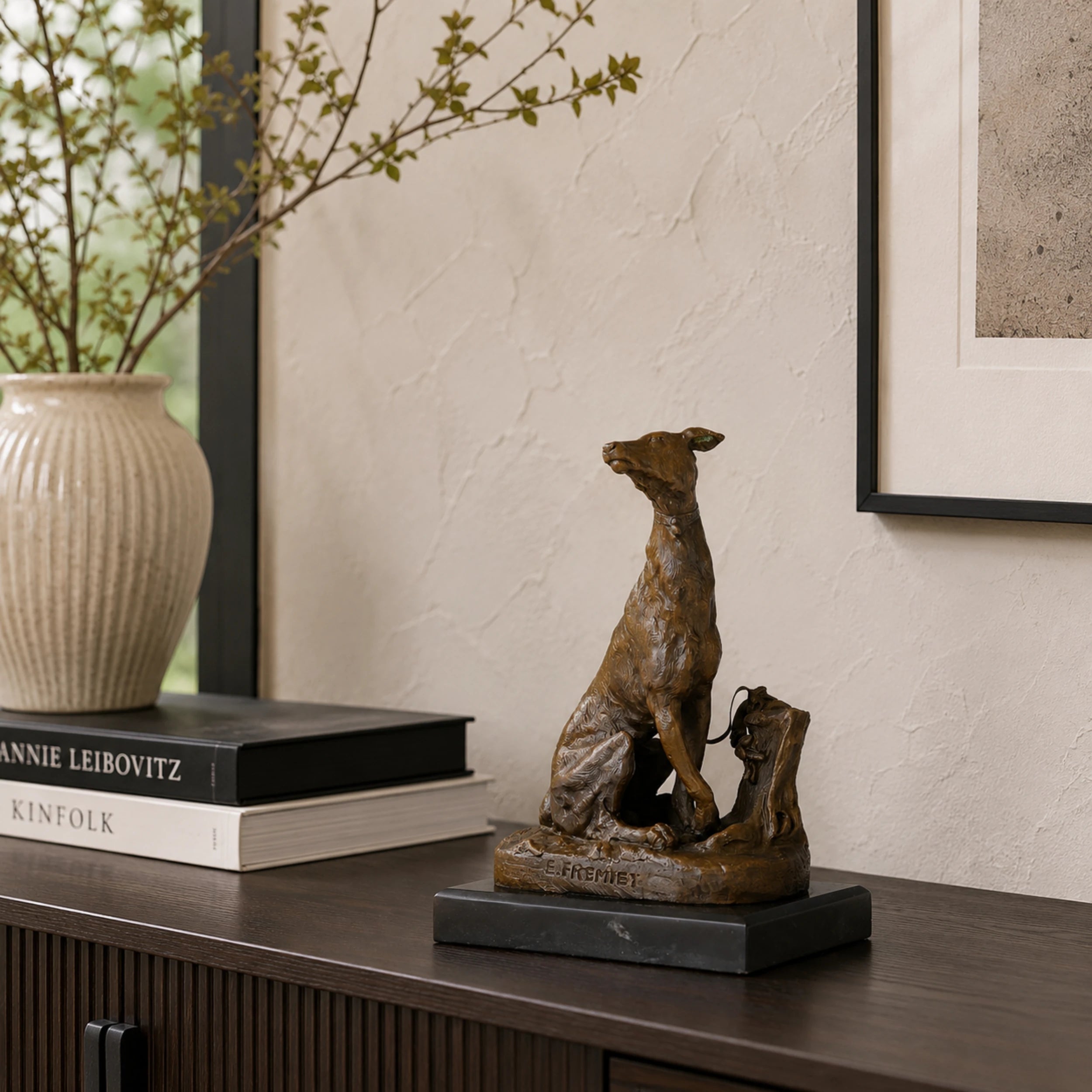 A refined bronze seated greyhound statue signed by Emmanuel Fremiet, mounted on a dark marble plinth for high-end home office or library decor.