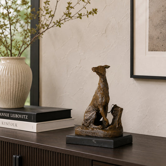 A refined bronze seated greyhound statue signed by Emmanuel Fremiet, mounted on a dark marble plinth for high-end home office or library decor.