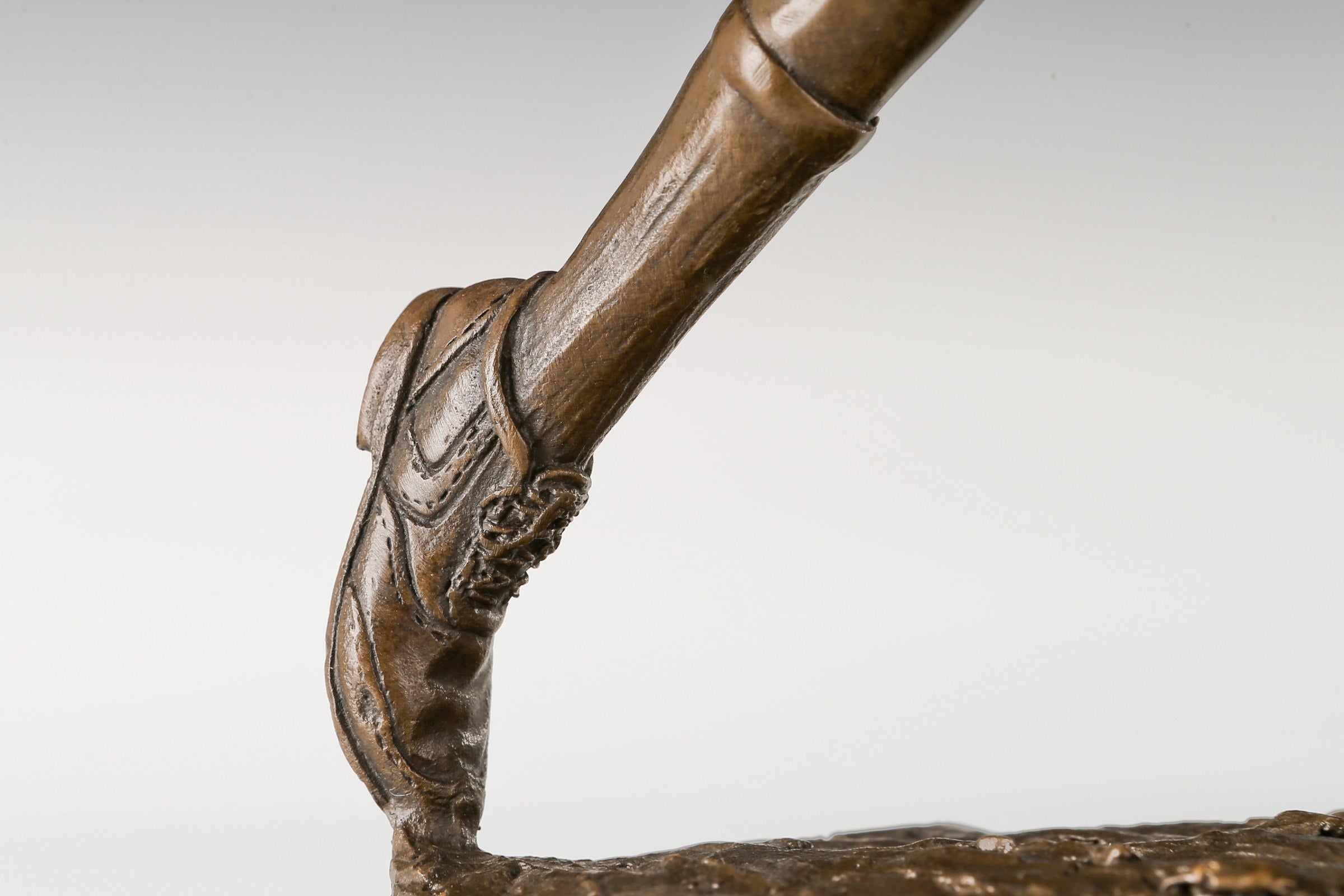 Black marble base and textured ground detail of female golfer bronze sculpture