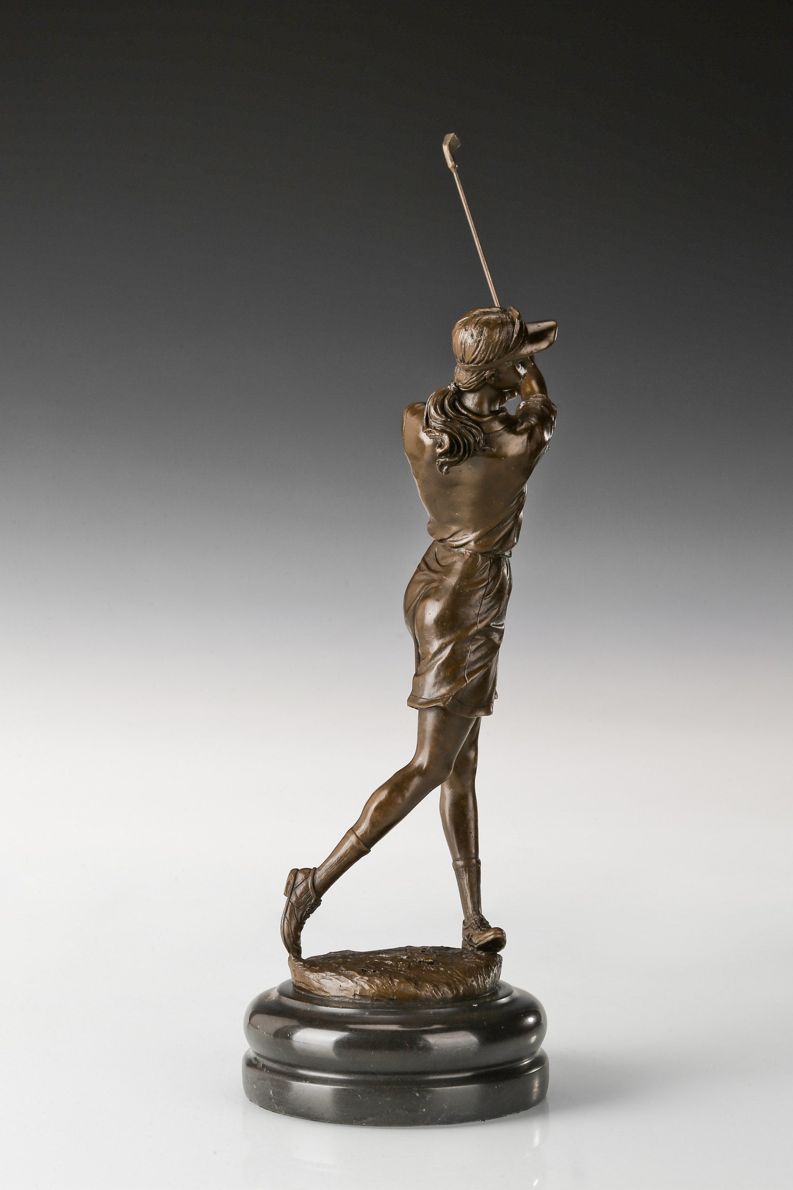 Female golfer bronze sculpture with raised golf club, rear-left view