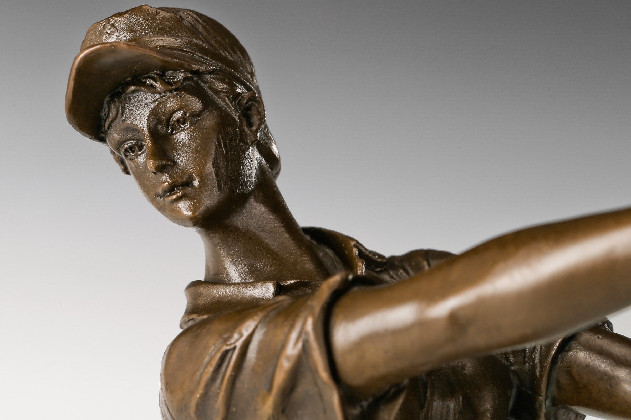 Side view of female golfer bronze sculpture completing a golf swing