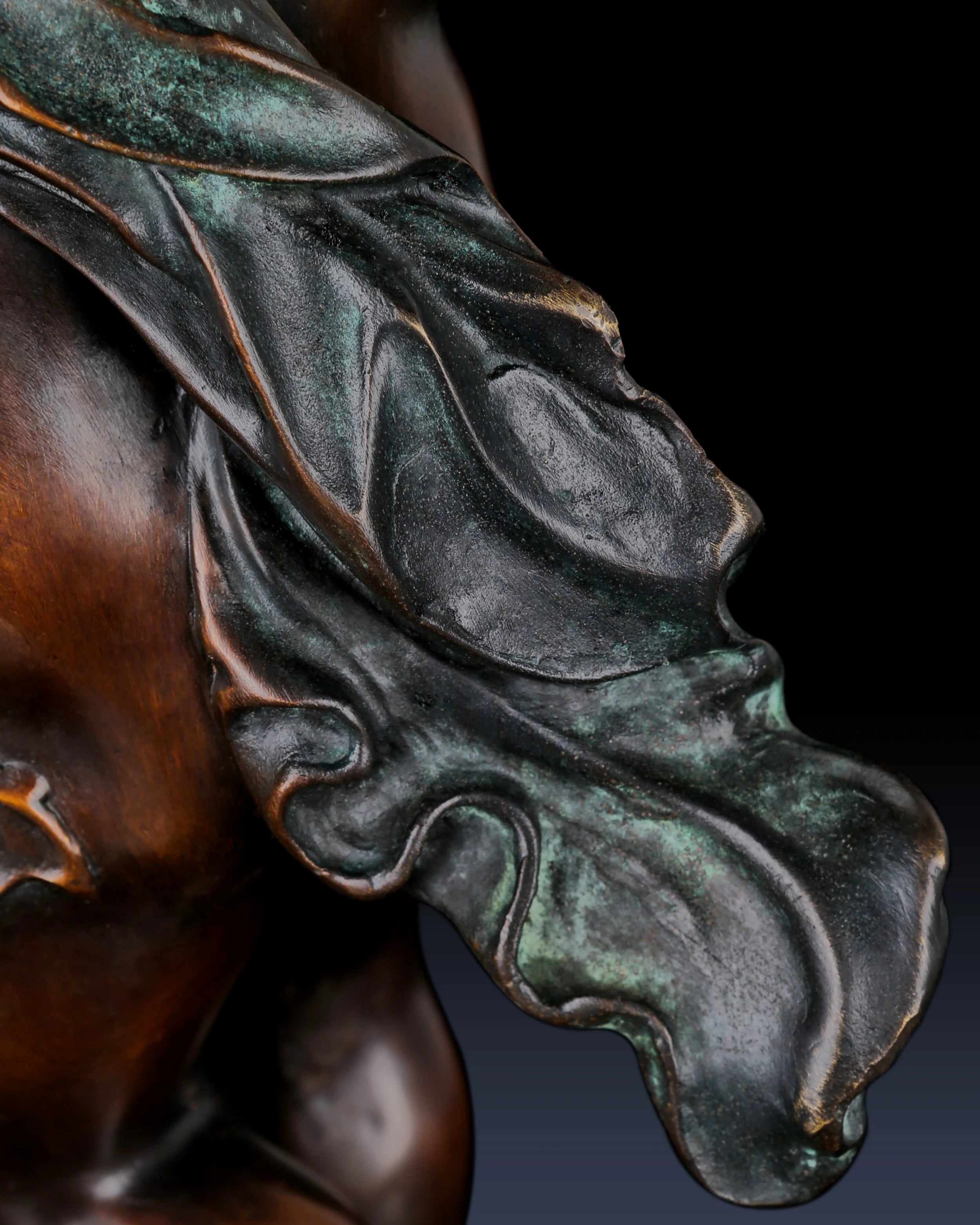 Detailed view of flowing drapery and hand-applied patina on bronze cherub sculpture