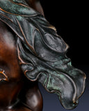 Detailed view of flowing drapery and hand-applied patina on bronze cherub sculpture
