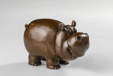 Angled view of a handcrafted bronze cow figurine with smooth rounded details.