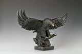 a majestic bronze sculpture of a bald eagle, crafted using the lost-wax casting method. The piece captures the raptor in a dynamic, predatory pose—wings fully spread, talons extended forward, and head tilted downward with a piercing gaze—conveying raw power, precision, and the primal intensity of a hunting strike.