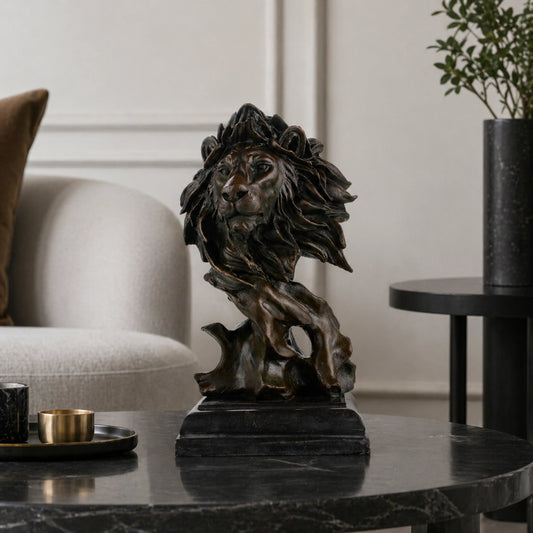 This striking bronze lion bust, crafted using the lost-wax casting method, captures the head and upper neck in a moment of quiet intensity. The flowing mane, detailed facial features, and deep bronze patina convey raw power, strength, and nobility. Mounted on a stepped dark marble plinth, the sculpture offers stability and presence, making it a distinguished accent for refined interiors or art collections.
