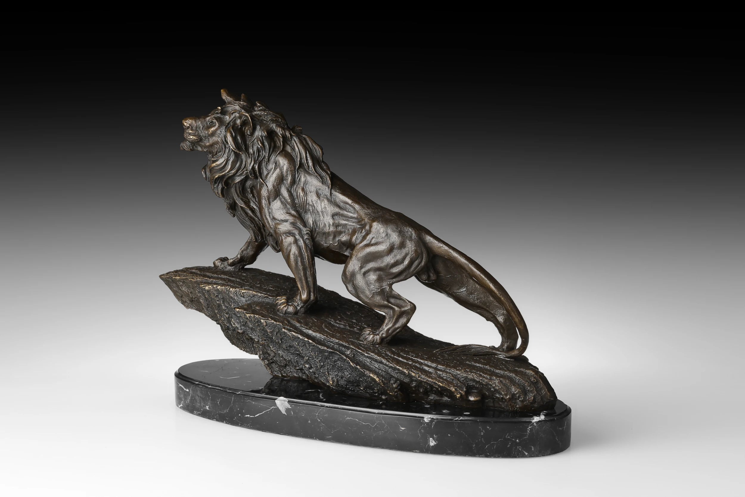 Angled view of majestic bronze lion statue walking across a rugged rock formation